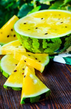 Sarı posalı karpuz. Tahta bir masada dilimlenmiş böğürtlen parçaları..