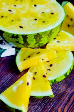 Sarı posalı karpuz. Tahta bir masada dilimlenmiş böğürtlen parçaları..