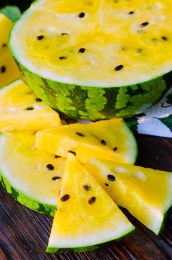 Sarı posalı karpuz. Tahta bir masada dilimlenmiş böğürtlen parçaları..