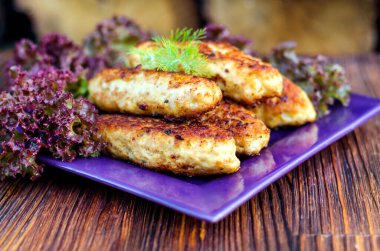 Tabakta tavuk pirzolası ve masada marul yaprakları.