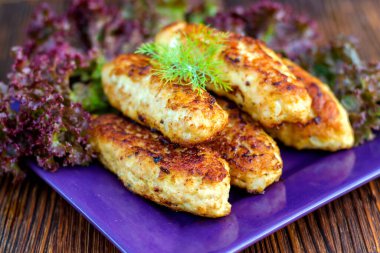 Tabakta tavuk pirzolası ve masada marul yaprakları.