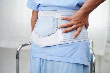 Asya baş ağrısı. Esnek destek kemeri takıp yürüteç takıyor..