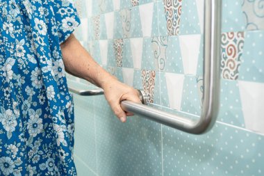 Asyalı yaşlı kadın banyoda güvenlik korkuluğu kullanıyor..