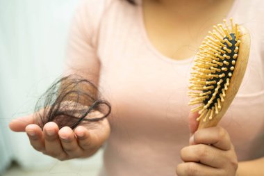 Asian woman have problem with long hair loss attach in her hand.