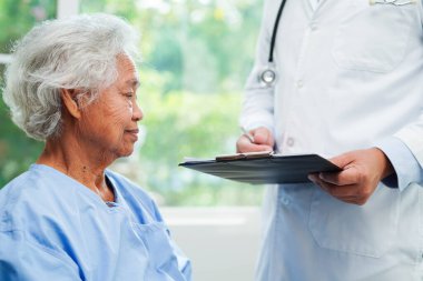 Klinikteki yaşlı kadın hastalarla ilgilenen, yardım eden ve onları cesaretlendiren doktor..