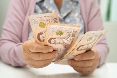 Retired elderly woman counting coins money and worry about monthly expenses and treatment fee payment.