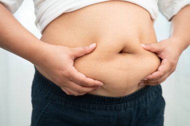 Asyalı kadın şişman göbeğini sıkmak için elini kullanıyor. Büyük boy aşırı kilolu ve obez..