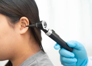 Otolaryngologist ya da ENT hekim doktoru yaşlı hasta kulağını otoskopla muayene ediyor, işitme sorunu var..