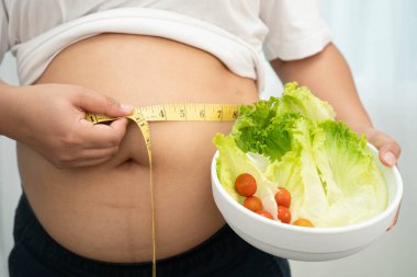 Koca göbekli, şişman, kilolu ve sağlıklı yiyecekleri olan Asyalı bir kadın..