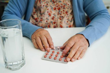 Asyalı yaşlı kadın bardakta suyla birlikte hap tutuyor. Sağlıklı, güçlü bir ilaç..