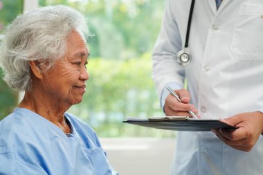 Klinikteki yaşlı kadın hastalarla ilgilenen, yardım eden ve onları cesaretlendiren doktor..