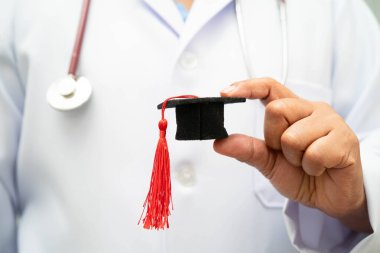 Hastanede elinde mezuniyet şapkası olan Asyalı kadın doktor. Tıp eğitimi konsepti..