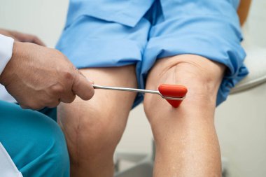 Asyalı doktor, hastanedeki yaşlı hastayı muayene etmek için diz refleksi sinirine vurdu..