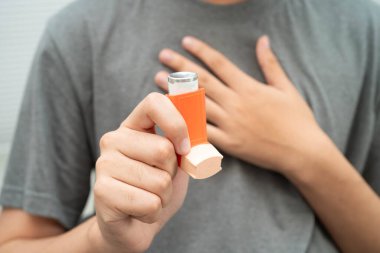 Astım ve kronik obstrüktif akciğer hastalığı KOAH, Asyalı genç ölçülü doz solunum cihazı kullanıyor..