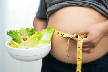 Koca göbekli, şişman, kilolu ve sağlıklı yiyecekleri olan Asyalı bir kadın..