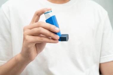 Astım ve kronik obstrüktif akciğer hastalığı KOAH, Asyalı genç ölçülü doz solunum cihazı kullanıyor..