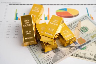 Gold bars on US dollar banknote money, finance trading investment business currency concept.