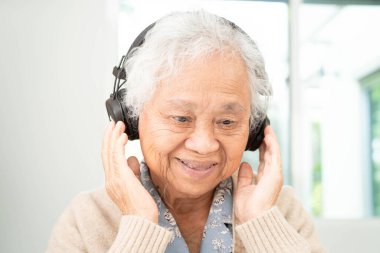 Asyalı son sınıf öğrencisi hasta, rahatlamak için kulaklık kullanmaktan mutluluk duyar..