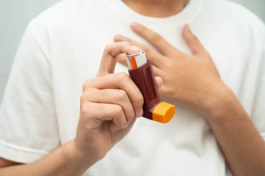 Astım ve kronik obstrüktif akciğer hastalığı KOAH, Asyalı genç ölçülü doz solunum cihazı kullanıyor..