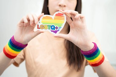 Gökkuşağı bayrağıyla LGBT kalbini tutan Asyalı kadın.
