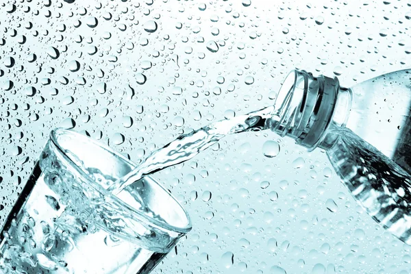 Trinkwasser wird aus einer Flasche in ein Glas gegossen — Stockfoto