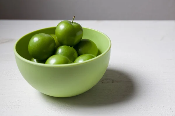 Gröna plommon i grön skål — Stockfoto