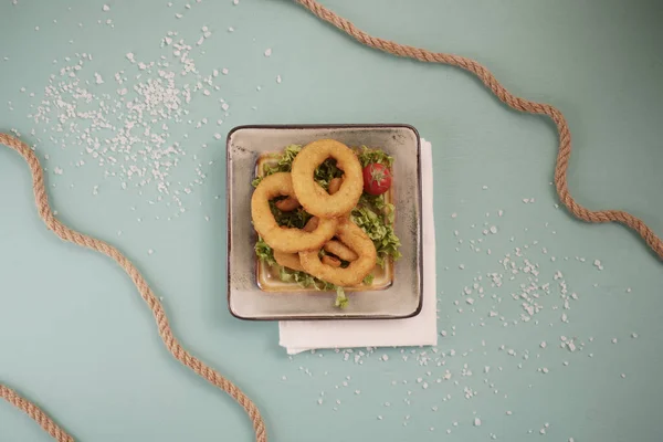 Geometrik bir tabakta mavi arka planda soğan halkaları. denizcilik teması