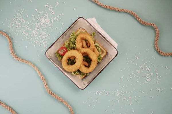 Geometrik bir tabakta mavi arka planda soğan halkaları. denizcilik teması