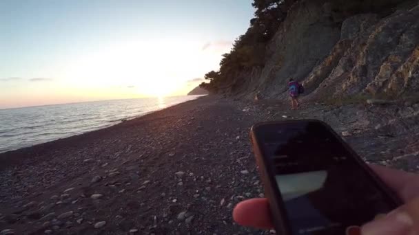 Κοιτάξτε στο τηλέφωνο σε ένα ηλιοβασίλεμα στην παραλία — Αρχείο Βίντεο