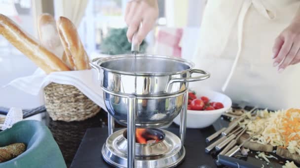 Female chef stirs fondue over low heat — Stock Video