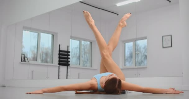 Dancer βρίσκεται στο πάτωμα του μπαλέτου στούντιο και κάνει προθέρμανση ασκήσεις για τα πόδια, χορεύτρια μπαλέτου, μπαλαρίνα στο στούντιο μπαλέτου, μάθημα χορού αίθουσα, 4k 60p Prores HQ — Αρχείο Βίντεο