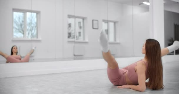 Dancer is sitting on the twine and warming up infront of the mirror wall in the white bright dance hall, ballet rehearsal, ballerina in the ballet studio, dance hall lesson, 4k 60p Prores HQ — Stock Footage Dancer is sitting on the twine and warming up infront of the mirror wall in the white bright dance hall, ballet rehearsal, ballerina in the ballet studio, dance hall lesson, 4k 60p Prores HQ Video Clip