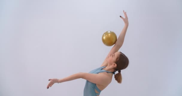 Žena atlet provádí kallisthenics cvičení s gymnastický míč na bílém pozadí, sportovní cvičení izolované, gymnastika v bílé hale, 4k 120p Prores HQ — Stock video