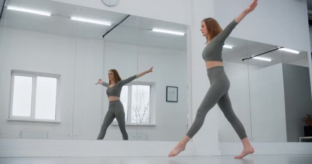 Dancer kvinna hoppar i slow motion framför spegelvägg, gymnastik i den vita danssalen, stretching tränare, yoga instruktör, 4k 120p Prores HQ — Stockvideo