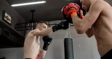 Düşük açılı atış: boksör eldivenli dövüşçü antrenörüyle antrenman yapıyor, kickboksörler antrenman yapıyor, 4k 120fps Prores karargahı