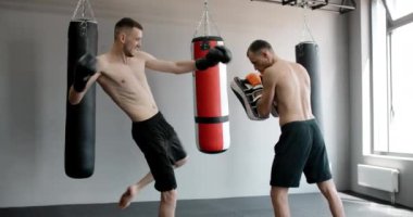 Kickboksör spor salonunda antrenörle diz darbesi pratiği yapıyor, kickboksörler antrenman yapıyor, 4k 120 fps Prores HQ