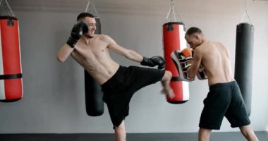 Kickboksör spor salonunda antrenörle diz darbesi pratiği yapıyor, kickboksörler antrenman yapıyor, 4k 120 fps Prores HQ