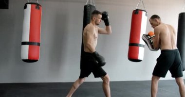 Kickboksör orta vuruşunu spor salonunda ağır çekimde antrenörle yapıyor, kickboksörler antrenman yapıyor, 4k 120 fps Prores HQ