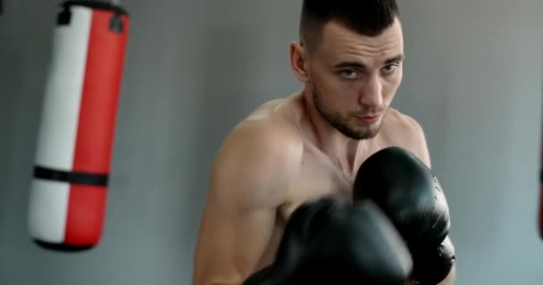 Kickboxer v boxerských rukavicích dělá stínový box a vlaky v boxerském klubu, bojovník bojuje se stínem, kickboxer trénink stávky v tělocvičně, 4k 60p Prores HQ — Stock video