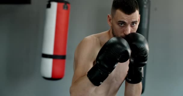 ボクシンググローブのキックボクサーは影のボクシングを行い、ボクシングクラブで訓練し、戦闘機の男は影と戦っている、ジムでキックボクサートレーニングストライキ、 4k 60p｜Prores HQ — ストック動画