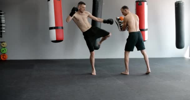 Steadicam tiro: kickboxer está praticando seu chute médio e golpe no joelho com treinador em câmera lenta no ginásio, kickboxers estão treinando, 4k 120fps Prores HQ — Vídeo de Stock