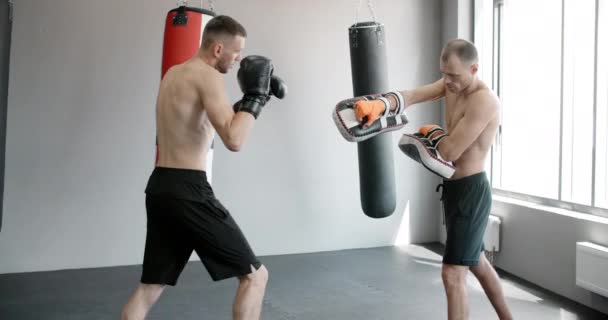 Kickboxer ćwiczy uderzenie kolana z trenerem w zwolnionym tempie na siłowni, zawodnik mieszanych sztuk walki trenuje, 4k 120fps Prores HQ — Wideo stockowe