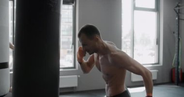 Karışık dövüş sanatları dövüşçüsü boksör çantasını ağır çekimde tekmeliyor, dövüşçü boks kulübünde antrenman yapıyor, 4k 120p Prores HQ