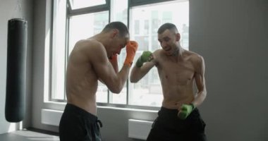 İki kickboksçu salonda ağır çekimde yumruk ve vuruşlarını çalışıyor, karma dövüş sanatları dövüşçüleri antrenman yapıyor, 4k 120fps Prores karargahı