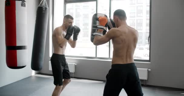 MMA vechter oefent zijn stakingen met trainer in slow motion in de sportschool, kickboxers trainen, 4k 120fps Prores HQ — Stockvideo