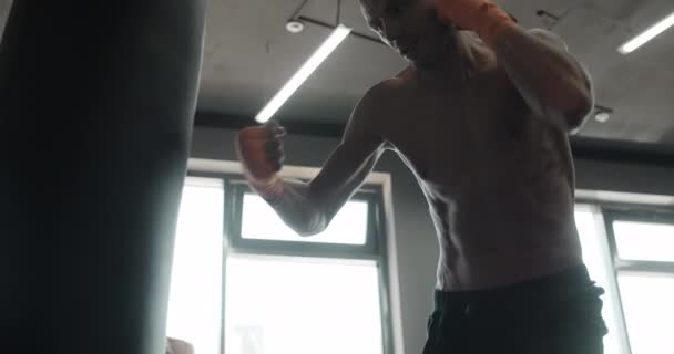 Боец смешанных единоборств бьет боксера кулаками и ногами в замедленной съемке, боец тренируется в боксерском клубе, 4k 120p Prores HQ — стоковое видео