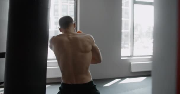 Fighter kickboxer dělá kruhový loket kop do boxerské tašky ve zpomaleném filmu, trénink v boxerském klubu, 4k 120p Prores HQ — Stock video