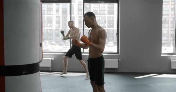 Двоє бійців кидають боксерські сумки в спортзалі в повільному русі, бійці змішаних бойових мистецтв тренуються, 4k 120fps Prores HQ — стокове відео