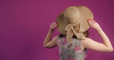 Yazlık elbisesi ve hasır şapkasıyla gülümseyen neşeli kadın pembe arka planda dönüyor, 4k Prores HQ 60p