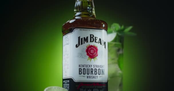Снимок с увеличением: отдельная бутылка бурбона Jim Beam с коктейлем на заднем плане, 4k 60p Prores HQ — стоковое видео